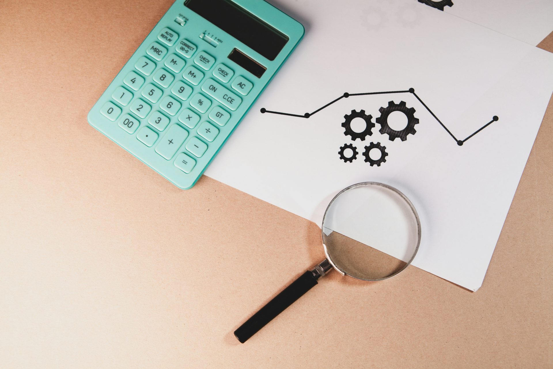 Calculator, magnifying glass, and chart with gears on paper